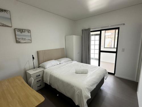 a white bedroom with a bed and a window at June Stay in Perth