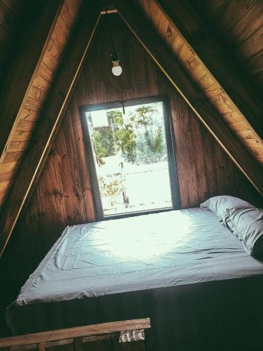 a bed in a wooden room with a window at La Empinada in Bialet Massé