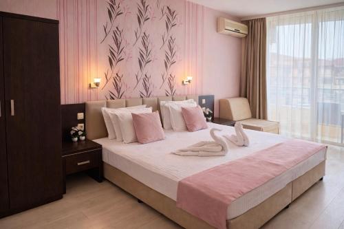 a bedroom with a large bed with two towels on it at Hotel Ancora Beach in Primorsko