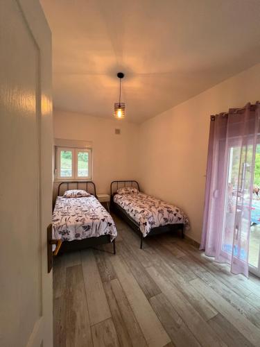 two beds in a room with two windows at Vila Oaza in Trebinje