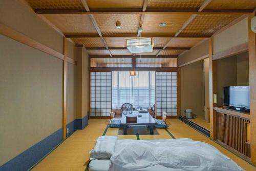 a large room with a bed and a tv in it at Hokkawa Onsen Hotel in Higashiizu