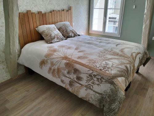 a bed with a comforter and pillows in a bedroom at Gîte la Bourgeoise in Bléré