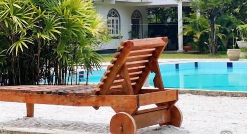 a wooden chair sitting next to a swimming pool at Benthota grand villa in Nakandalagoda