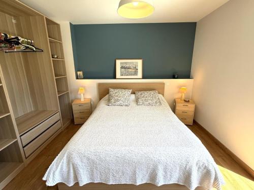a bedroom with a white bed with two lamps at Le gîte de la battère in Saubusse