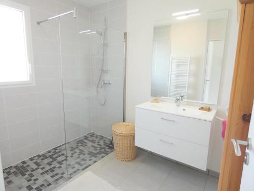 a white bathroom with a shower and a sink at Le gîte de la battère in Saubusse