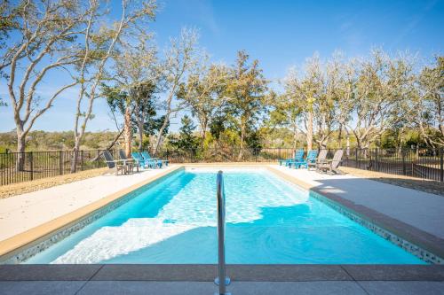 a swimming pool with blue chairs and trees at Beach 45 by Oak Island Accommodations in Oak Island