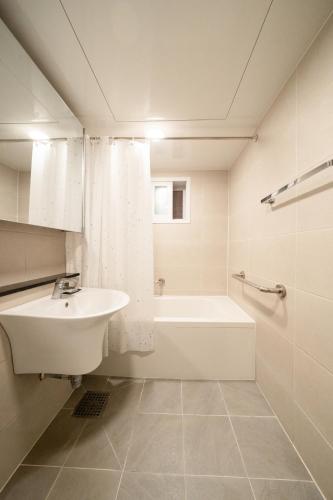 a white bathroom with a sink and a bath tub at Banghwa Space 5 min to Banghwa Stn, Near Gimpo Airport, Magok & COEX in Seoul
