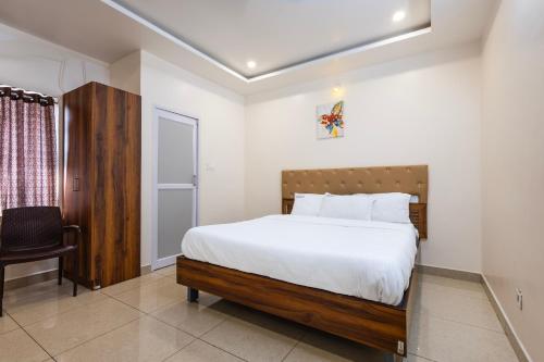 a bedroom with a large bed and a chair at Cannan Residency Pondicherry in Pūrnānkuppam