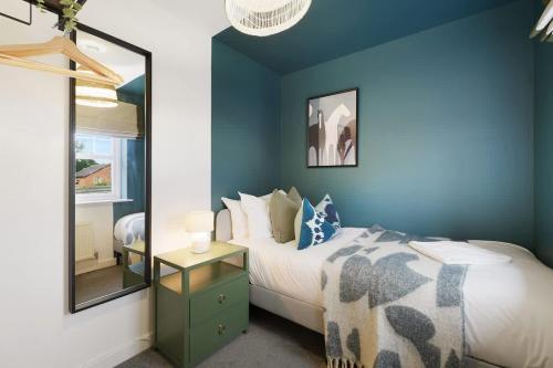 a blue bedroom with a bed and a mirror at Stylish Teesside Home Ideal for Work or Leisure in Stockton-on-Tees
