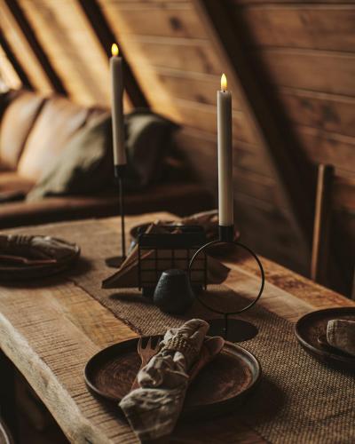 a wooden table with two candles and plates on it at BRUN Cabin in Şotrile