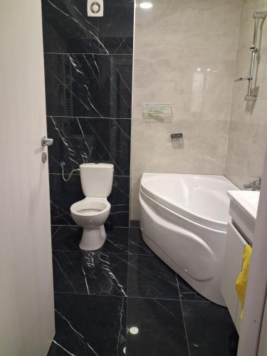 a bathroom with a toilet and a tub and a sink at Modern 1-Bedroom Apartment with AC, Free Parking & Self Check-in Bucharest-Militari in Dudu