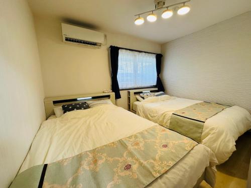a bedroom with two beds and a window at つんまぁー家 in Miyakojima