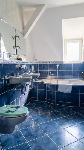 a blue tiled bathroom with two sinks and a toilet at Pension Arietta in Plauen