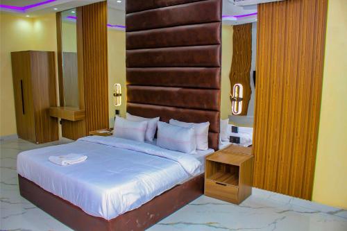 a bedroom with a large bed with a wooden headboard at Soulmate Hotels and Suites in Mawere