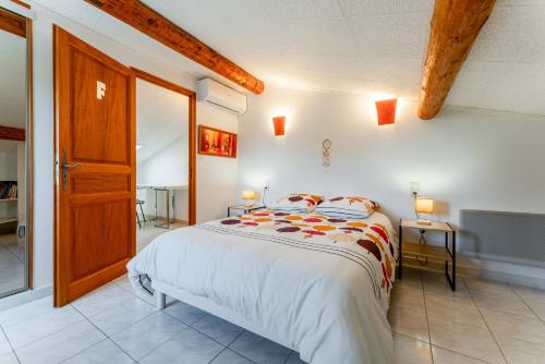 a bedroom with a bed and a wooden door at Maison proche Vaison la Romaine in Saint-Romain-en-Viennois