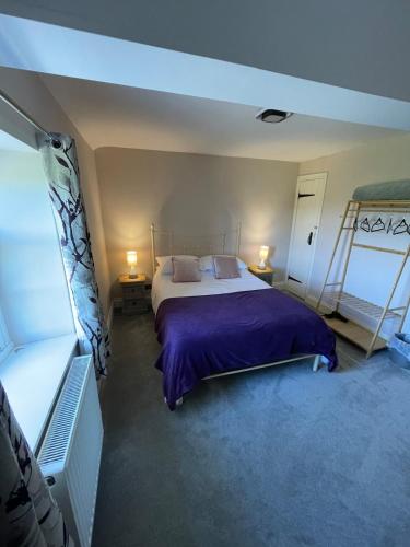 a bedroom with a large bed with purple sheets at Delightful detached 2 bedroom cottage in Grantley
