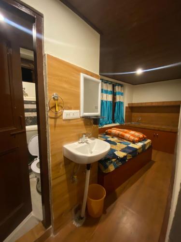 a small bathroom with a sink and a bed at Nature Nest in Manāli