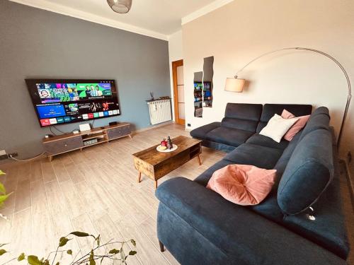 a living room with a blue couch and a flat screen tv at Panoramic Terrace & Sea View Flat with Free Parking in Genoa
