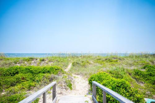a stairway to the beach with a boardwalk leading down to the beach at Beach Buzz by Oak Island Accommodations in Caswell Beach