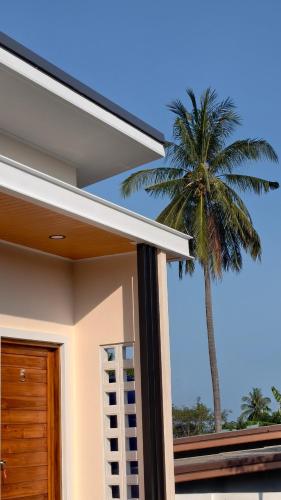 a palm tree in front of a house at ยินดีรีสอร์ท Yindee Resort in Don Sak