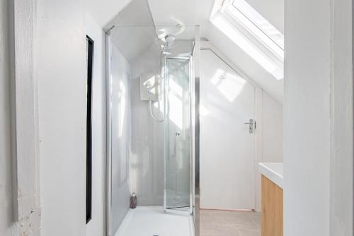 a glass shower stall in a white bathroom at Crafters Cottage in Sandwich