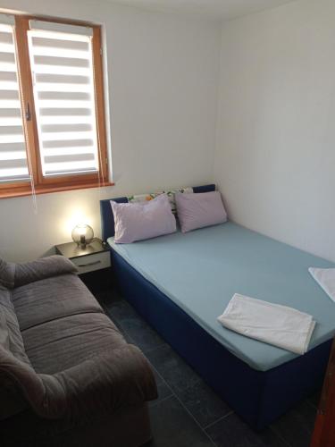 a small bedroom with a bed and a couch at Guesthouse Behar in Sarajevo