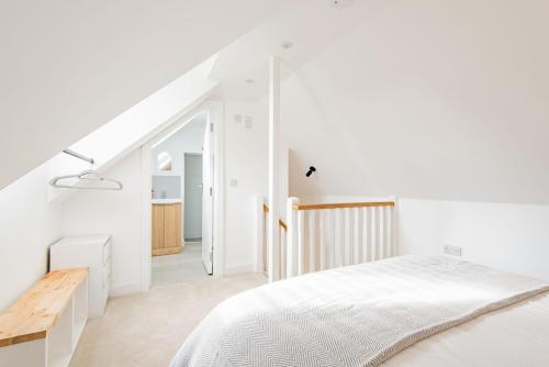 a white bedroom with a bed and a staircase at Crafters Cottage in Sandwich
