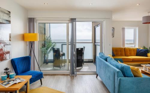 a living room with blue furniture and a view of the ocean at Colonels Rest - Luxury Beachside Townhouse with Sea Views in Sandown, Sleeps 10 in Sandown