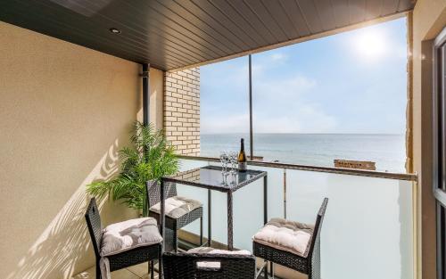 a balcony with a table and chairs and the ocean at Colonels Rest - Luxury Beachside Townhouse with Sea Views in Sandown, Sleeps 10 in Sandown