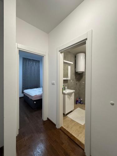 a white room with a bed and a bathroom at Apartman S in Vrnjačka Banja