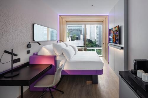 a bedroom with a bed and a desk and a bed and a window at YOTEL Bangkok Sukhumvit in Ban Nong Chaeng