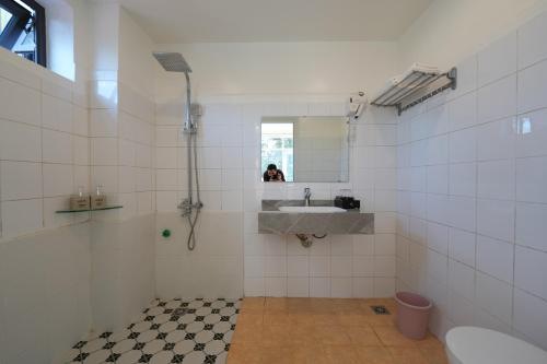 a white tiled bathroom with a sink and a mirror at Cong Fu Hotel in Bắc Hà