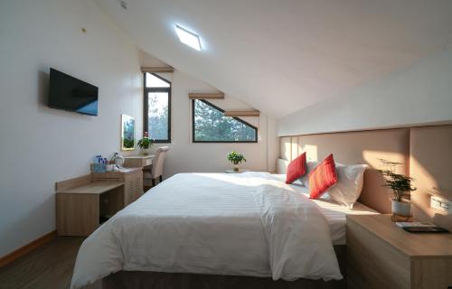 a bedroom with a large white bed and a desk at Cong Fu Hotel in Bắc Hà