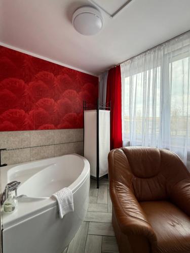 a bathroom with a tub and a chair and a couch at AtmosferA in Bydgoszcz