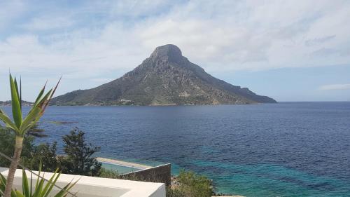 a mountain in the ocean with a swimming pool at Louis Studios Armeos in Masouri