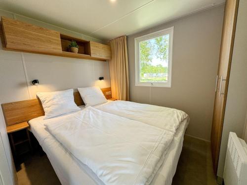 a bedroom with a large white bed with a window at Chalet Duin & Zee 44, Renesse in Renesse