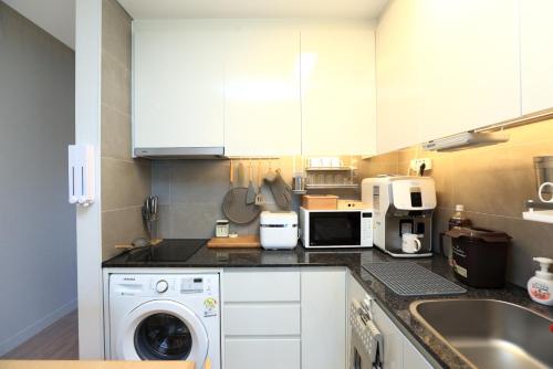 a kitchen with white cabinets and a washer and a sink at Farms Village in Jeju