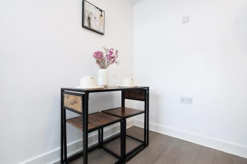 a black shelf with a vase of flowers on it at Studio - Kitchen - Parking - Ideal for Contractors in Swansea