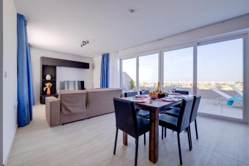 a dining room with a table and a living room at Superlative 3BR Penthouse, Private Pool and Views in Hal Ghaxiak