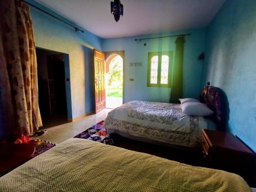 a bedroom with two beds in a room with a window at Écolodge OASIS Vallée du ZIZ Gîte DAR UL in Maarka