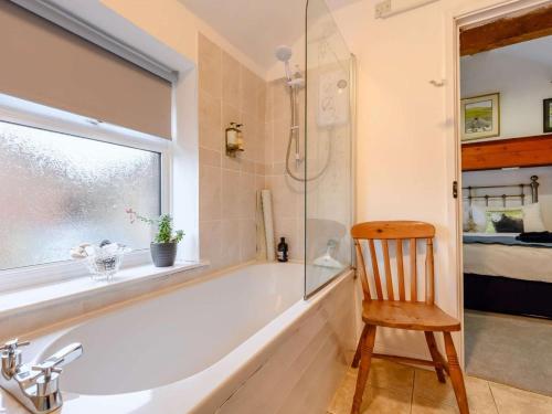 a bathroom with a tub and a chair and a window at 1 Bed in Penrith oc-90416 in Kirkoswald