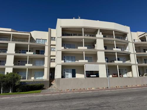 a large white apartment building in front of a street at 25 Sunset View in Langstrand