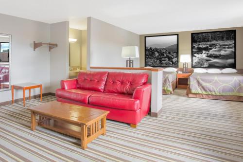 a living room with a red couch and a bed at Super 8 by Wyndham Abingdon VA in Abingdon