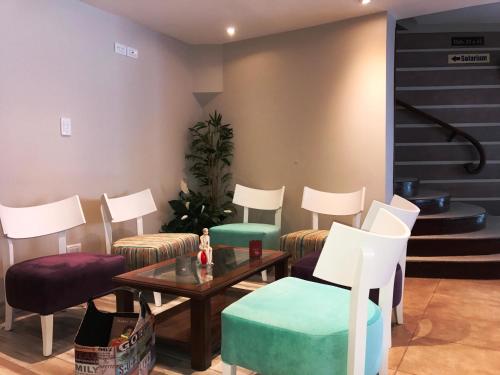 a waiting room with chairs and a table and stairs at Hotel Don Carlos in Villa Gesell