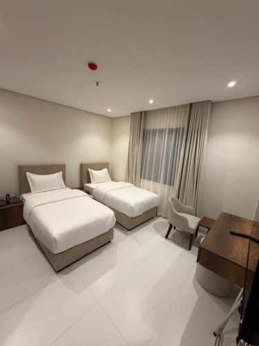a hotel room with two beds and a desk at توليب حتا 2 Tulip Hatta in Al Khobar