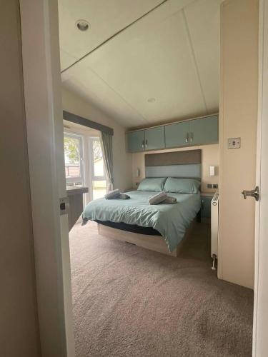 a bedroom with a bed with green sheets and a window at JLUX Lodges in Crowle