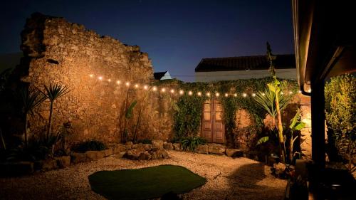 a courtyard with a stone wall with a string of lights at Villa familiar com piscina e jacuzzi a 30 min de Lisboa in Torres Vedras