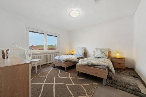 a bedroom with two beds and a desk and a window at Ferienwohungen Otto und Grete in Hemmoor
