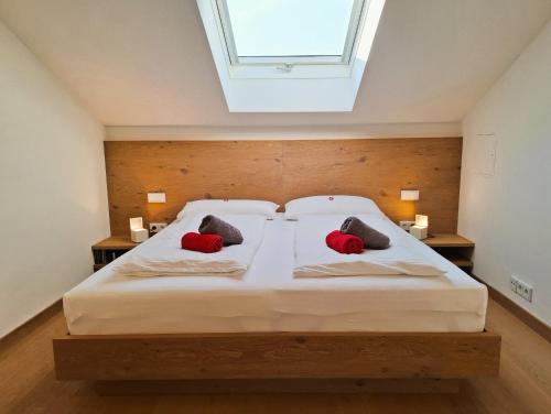 a bedroom with a large bed with two red pillows at Bodenschneidsuiten Luxburg in Tegernsee