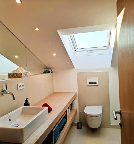 a bathroom with a sink and a toilet with a skylight at Bodenschneidsuiten Luxburg in Tegernsee